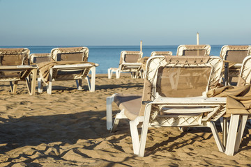 Sun loungers and closed umbrellas at a seaside resort , the calm and relaxed atmosphere of the summer holiday at sunset