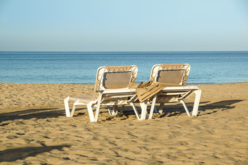 Sun loungers and closed umbrellas at a seaside resort , the calm and relaxed atmosphere of the summer holiday at sunset