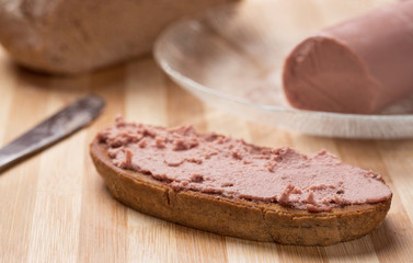Liver spread on a slice of Rye bread with liver spread and Rye bread in background