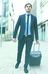 cheerful worker in suit going with bag