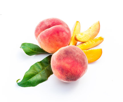Fresh ripe peaches, whole and sliced, with leaves, on white background.