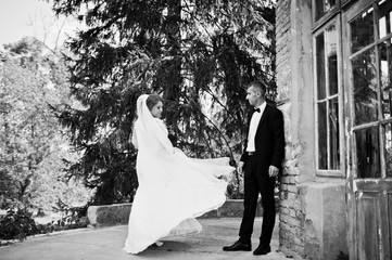 Romantic lovely newly married couple posing by the medieval castle on their wedding day. Black and white photo.