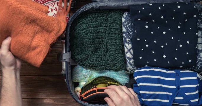 Man packing a luggage for winter holidays for his girlfriend. Timelapse