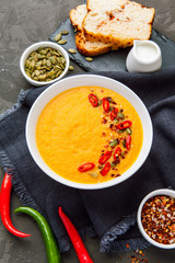 Pumpkin soup in white plate with spice on dark background