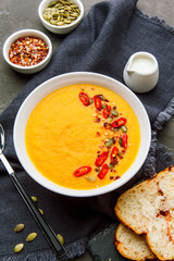 Pumpkin soup in white plate with spice on dark background