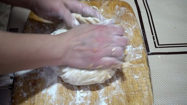 4k view of female hands kneading dough on a wooden board on the table