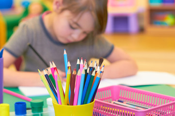 A cute child in a kindergarten draws at a table