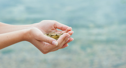 Panorama of  Handful of coins in palm female hands. Concept of saving and passive income.