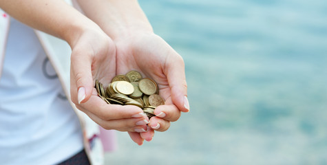 Panorama of  Handful of coins in palm female hands. Concept of saving and passive income.