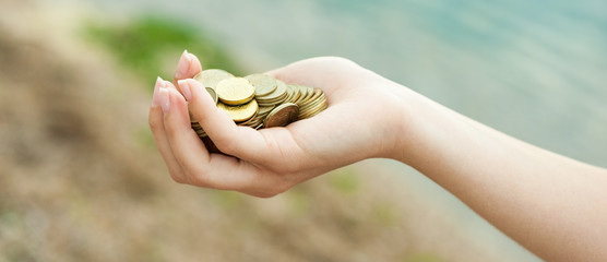 Panorama of  Handful of coins in palm female hands. Concept of saving and passive income.