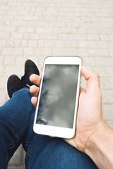  Man hand using a smart phone outdoors. The man sitting on the benchand wait for the meeting with a person