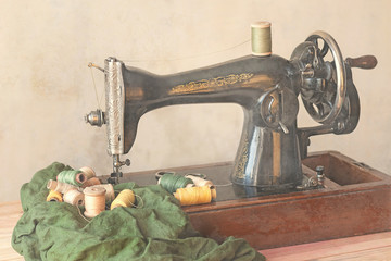 Old sewing machine, fabric and sewing thread in vintage style.