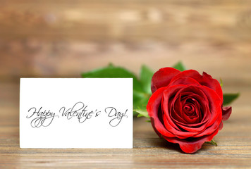 Happy Valentines Day text on paper card and red rose. Creative love concept.