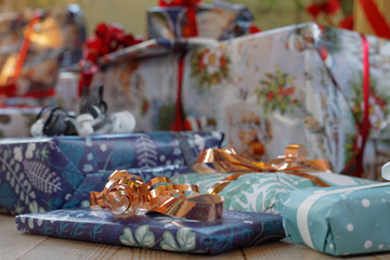 Pile of Christmas presents wrapped in colorful gift paper decorated with golden ribbon. Short depth of focus