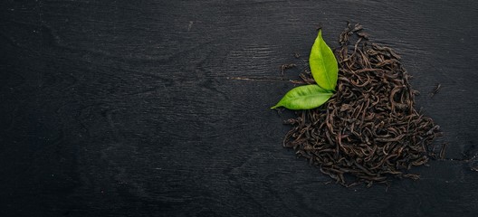 Dry black tea. On a wooden background. Top view. Copy space.