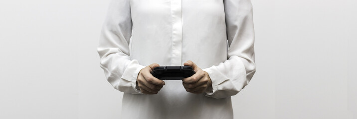 Black gamepad in the woman's hands on the white background. Gaming video game. Selective focus and shallow DOF