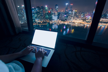  Woman freelancer is working using laptop computer in home office at night. Aerial city skyline...