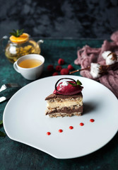 Ukrainian traditional and modern dessert Kiev cake with berry sorbet, with berries and tea on a green concrete background