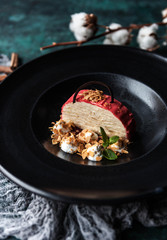 Napoleon cake with raspberries in a black matte plate on a green concrete background