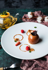 dessert Caramel mousse with tea kettle on a green concrete background