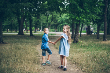 Naklejka na ściany i meble A little boy and girl walking together and holding each other hands