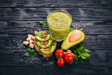 Sandwich with avocados, eggs, cherry tomatoes and pistachios. Kiwi juice. On a wooden background. Top view. Free space for your text.