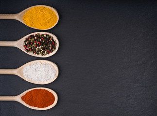 Top view mix indian spices in wooden spoons  on a black background