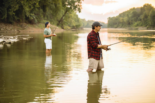 Side View Of Male Friends Fishing In Lake