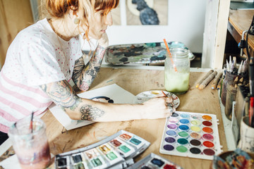 Side view of artist painting while standing at table in studio