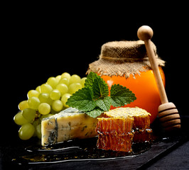 honey, cheese and grapes on a black background