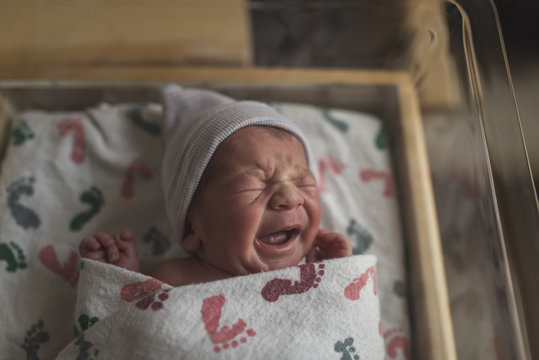 Close Up Of Newborn Baby Boy Crying In Crib At Hospital