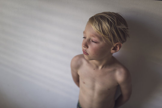 High angle view of shirtless boy standing by wall at home