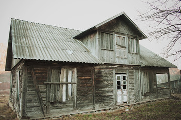 Fototapeta na wymiar Abandoned old wooden house in a rural field in Ukraine. Broken vintage wood building. Side view.