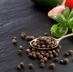 black pepper peas  in a spoon on a black background