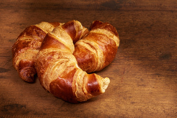 Freshly baked croissants on wooden cutting board, close-up.