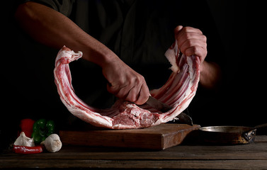 Man cutting raw rack of  lamb meat