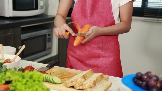 hand of woman peel carrots with a knife in kitchen room