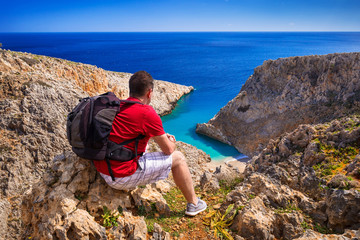 Man with backpack watching beautiful beach on Crete, Greece