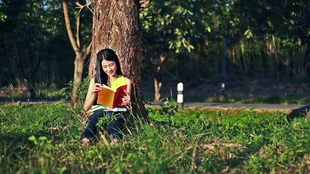 woman sitting on grass and reading a book in the garden