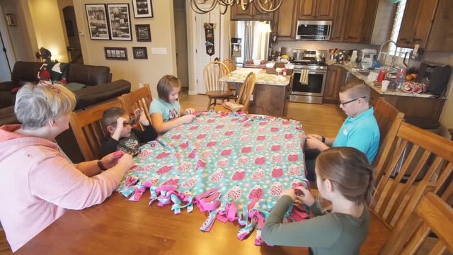 Kids help grandmother tie a quilt