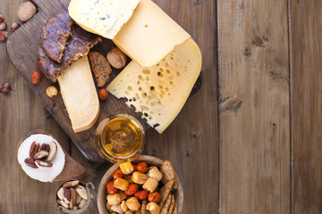 different cheese classic choice, on an old wooden board, nuts, snacks and a glass of beer