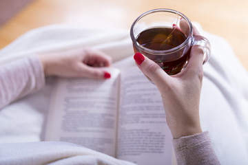 women drink tea and read a book wrapped in blankets