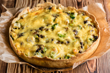 Laurent pie with chicken, mushrooms and broccoli on a wooden table