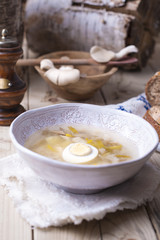 white plate with soup with mushrooms and egg. Wooden background, bread and spices
