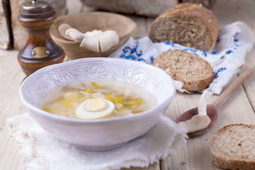 Obraz na płótnie Canvas white plate with soup with mushrooms and egg. Wooden background, bread and a spoon