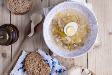 white plate with soup with mushrooms and egg. Wooden background, bread and spices