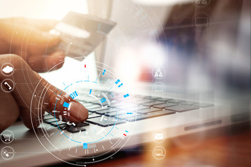 Close up of Hand using credit card and laptop computer on wooden desk with VR icon chart graph diagram