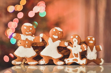 Happy ginger cookies family on the background of New Year tree. Concept of Christmas holidays. Bokeh background. Toned image.