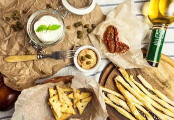Different types of snacks, grissini, cheese crackers, capers, dried tomatoes and different types of sauces