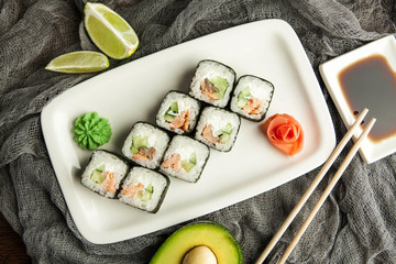 Japanese sushi rolls with soy sauce and chopsticks on a gray napkin